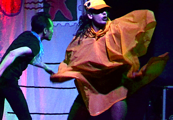 a performer dressed vaguely as a duck (with a yellow baseball cap and yellow raincoat) dancing wildly