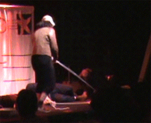 a moving clip from the play, one Amelia is standing, surrounded by several Amelias laying on the ground. The standing Amelia hoists a rope above her head, as she does, it is revealed that the rope is attached to all of the fallen Amelias, whose limbs raise as the rope raises, but they are unable to fully stand.